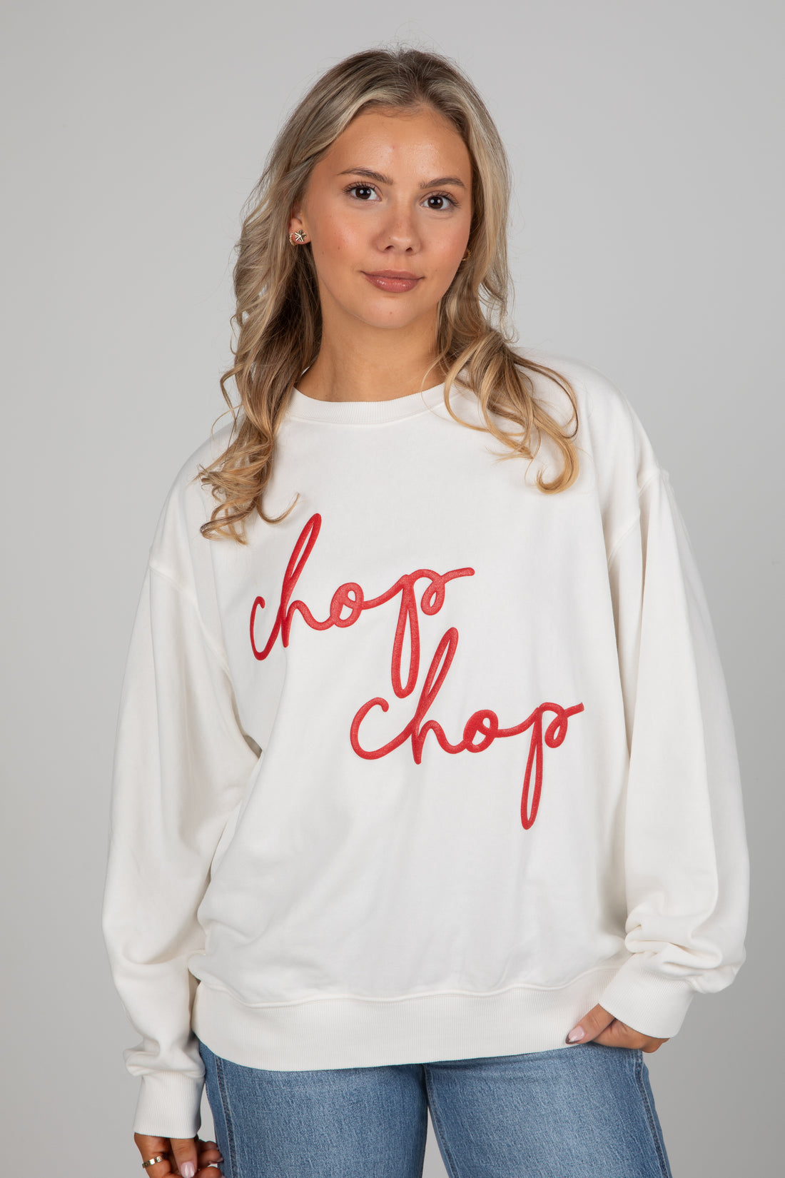 Woman wearing a white sweatshirt with red text &