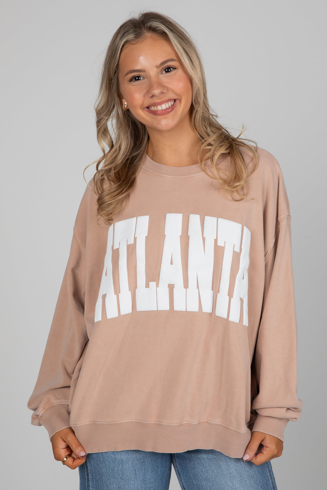 Woman wearing a beige sweatshirt with &