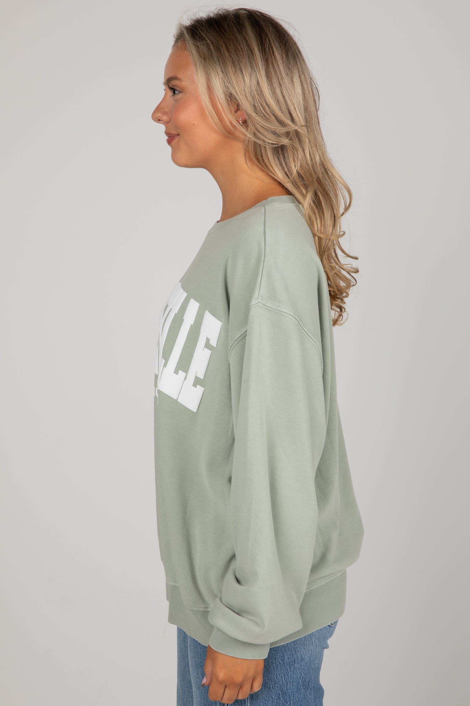 Person wearing a light green sweatshirt with text on a plain background