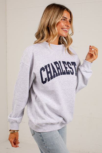 A woman wearing a light heather gray sweatshirt with &