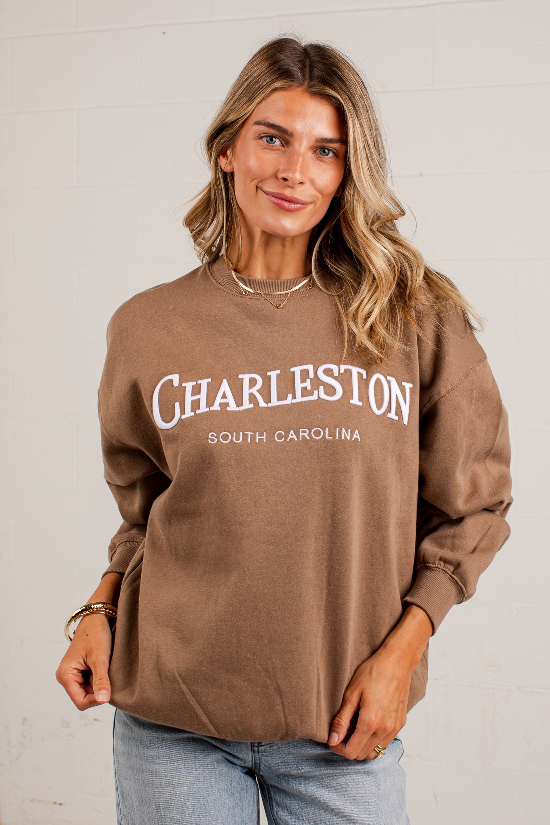 A woman wearing a brown long-sleeve sweatshirt with &