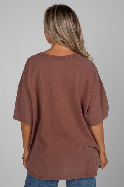 Person wearing a brown oversized t-shirt on a plain background