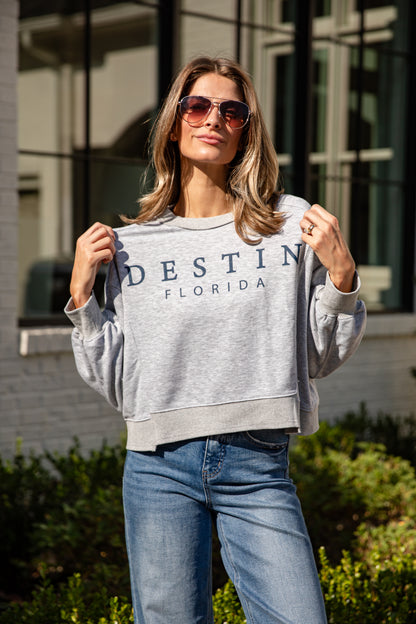 Woman wearing a gray sweatshirt with &