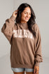 A woman wearing a brown sweatshirt with &