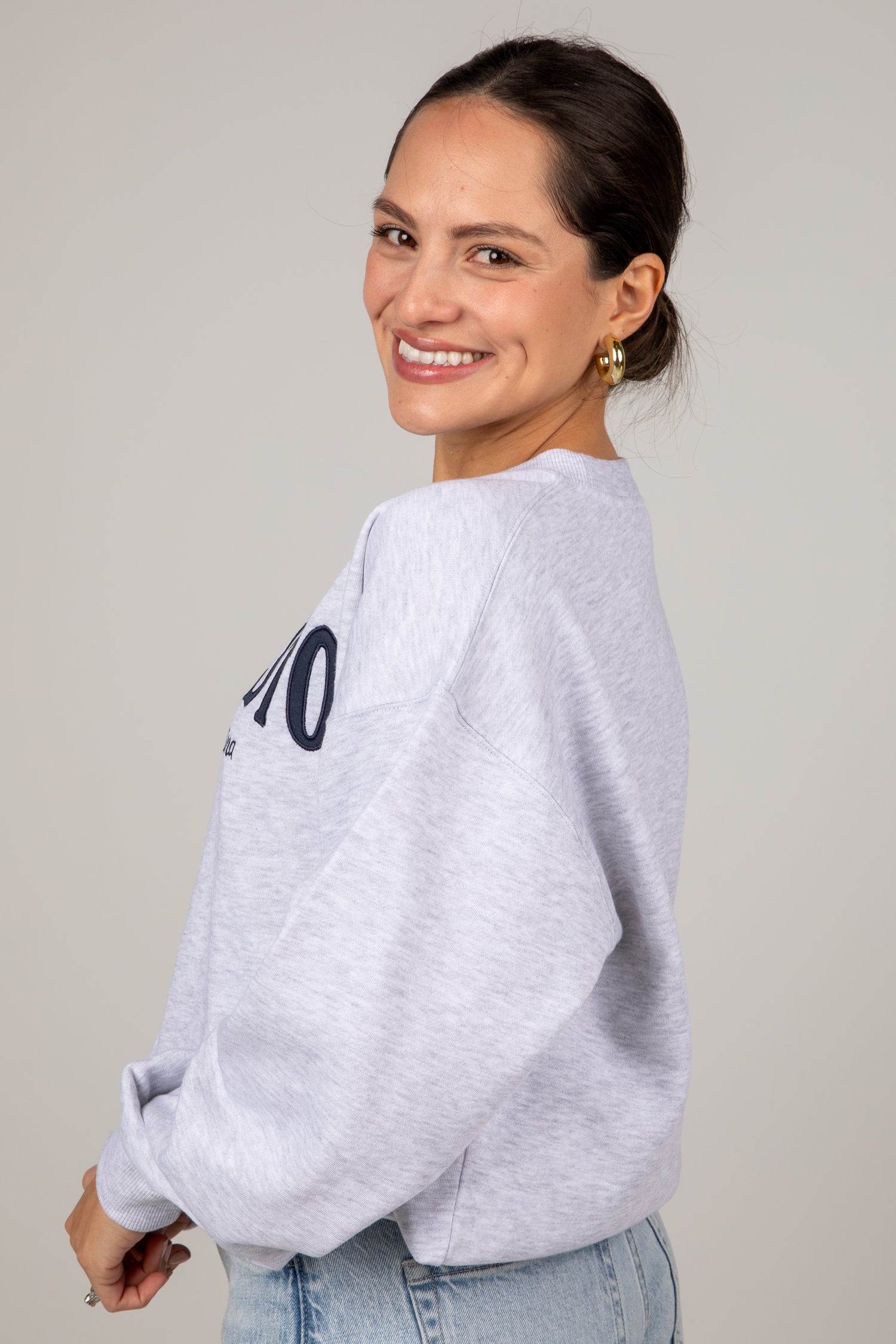 Woman wearing a light gray sweatshirt with &