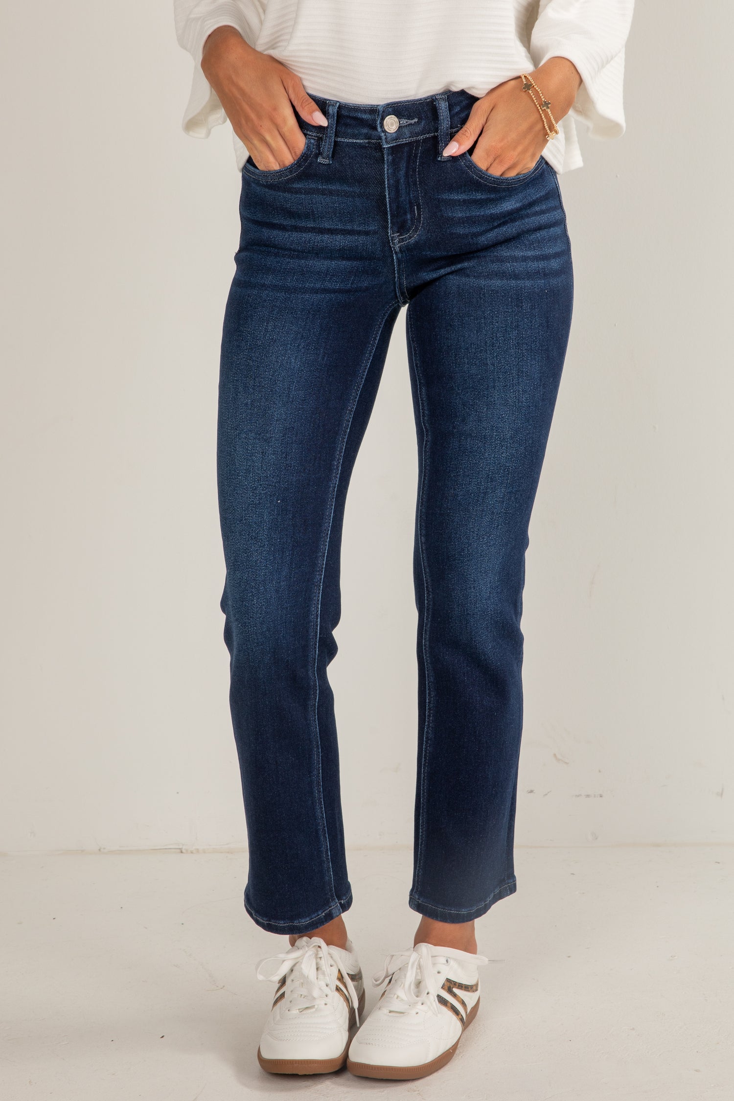 Person wearing blue jeans and white sneakers on a plain background