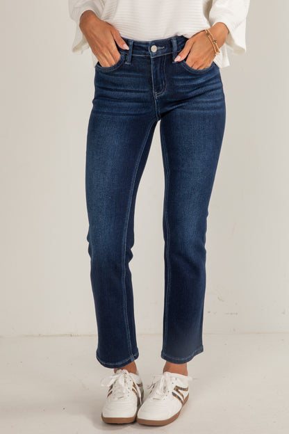 Person wearing blue jeans and white sneakers on a plain background