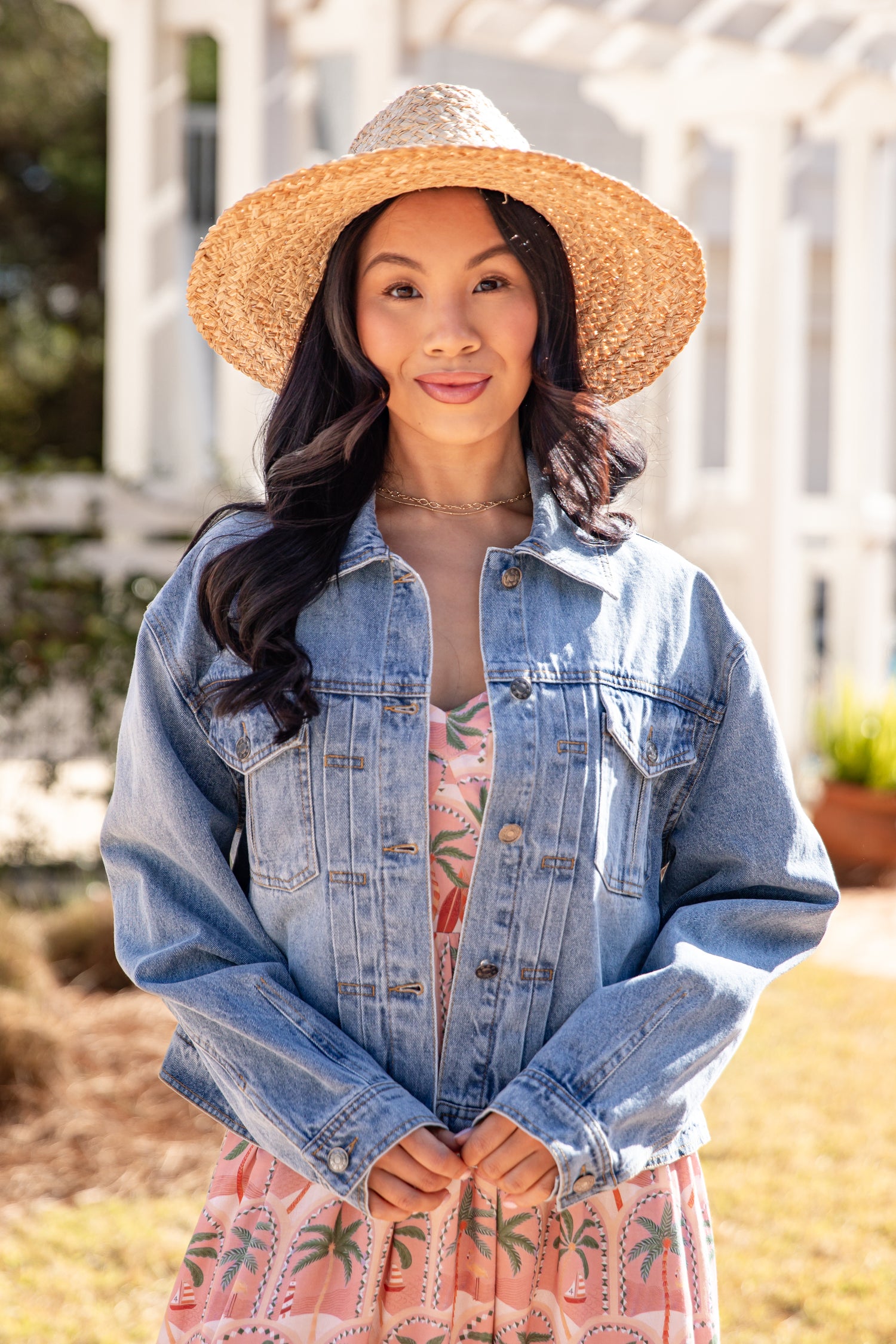 Woman wearing a denim jacket and straw hat outdoors
