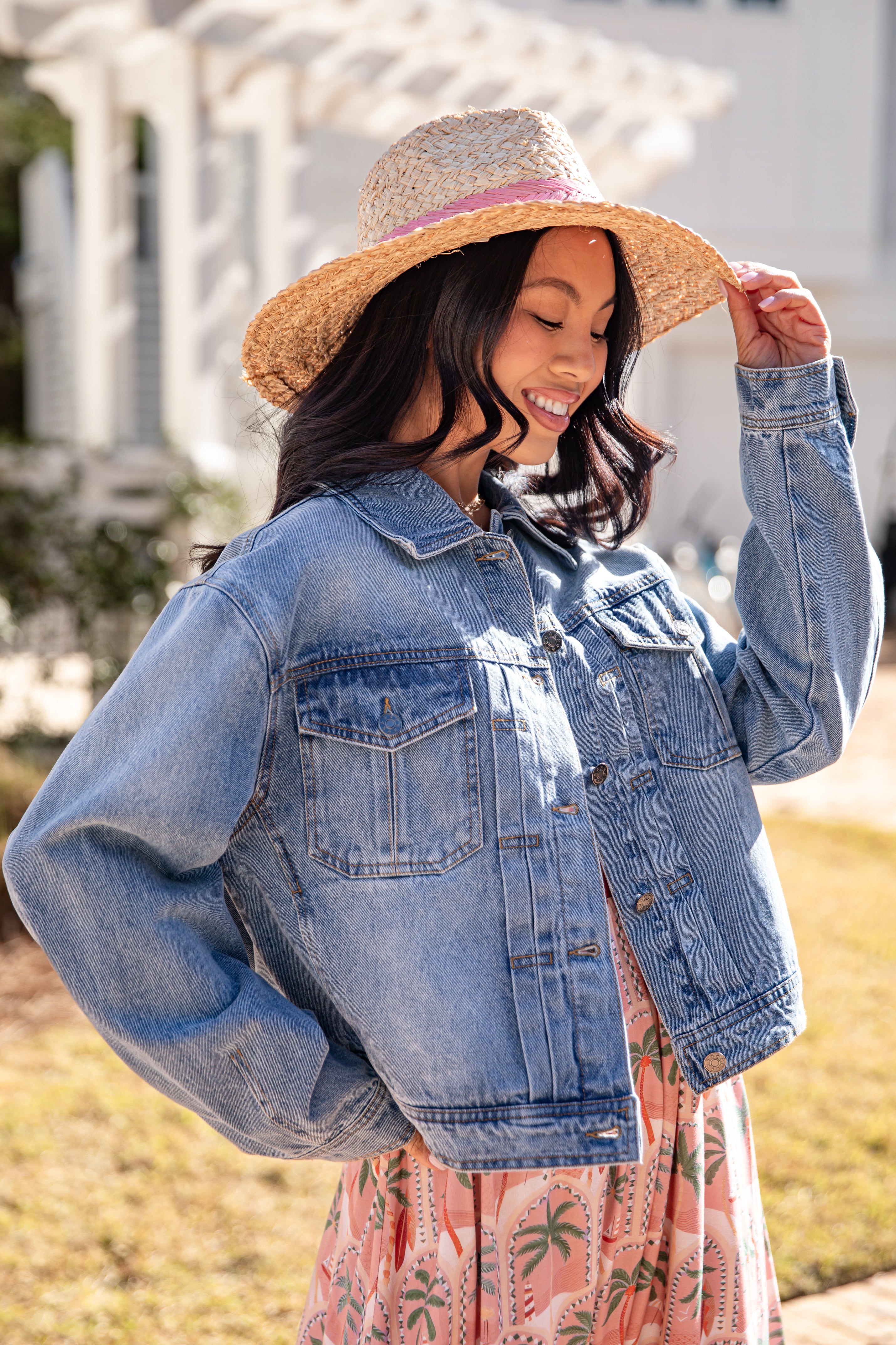 Woman wearing a denim jacket and straw hat outdoors