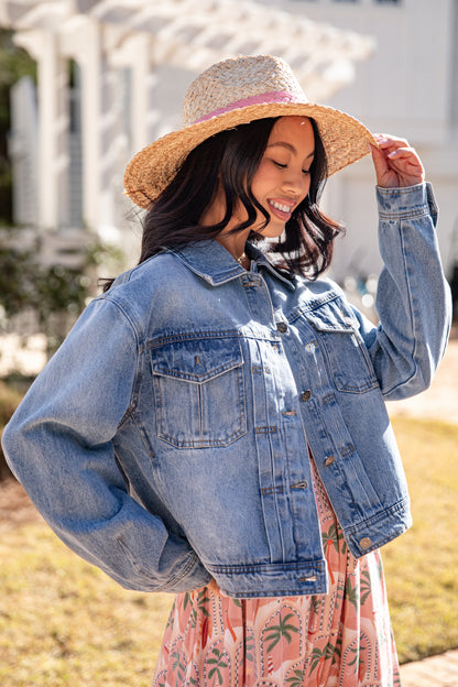 Woman wearing a denim jacket and straw hat outdoors
