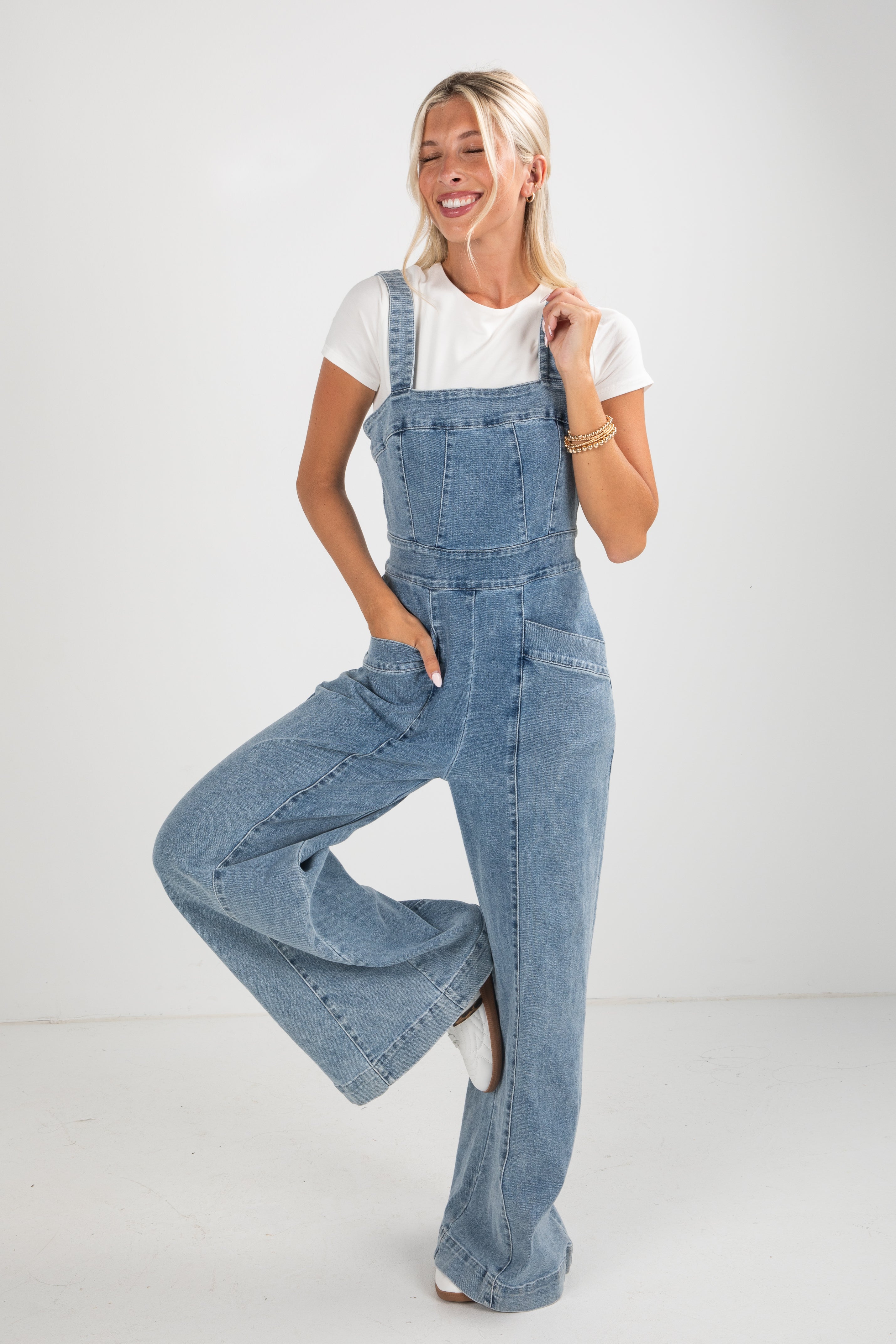 Woman wearing blue denim overalls on a white background