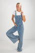 Woman wearing blue denim overalls on a white background