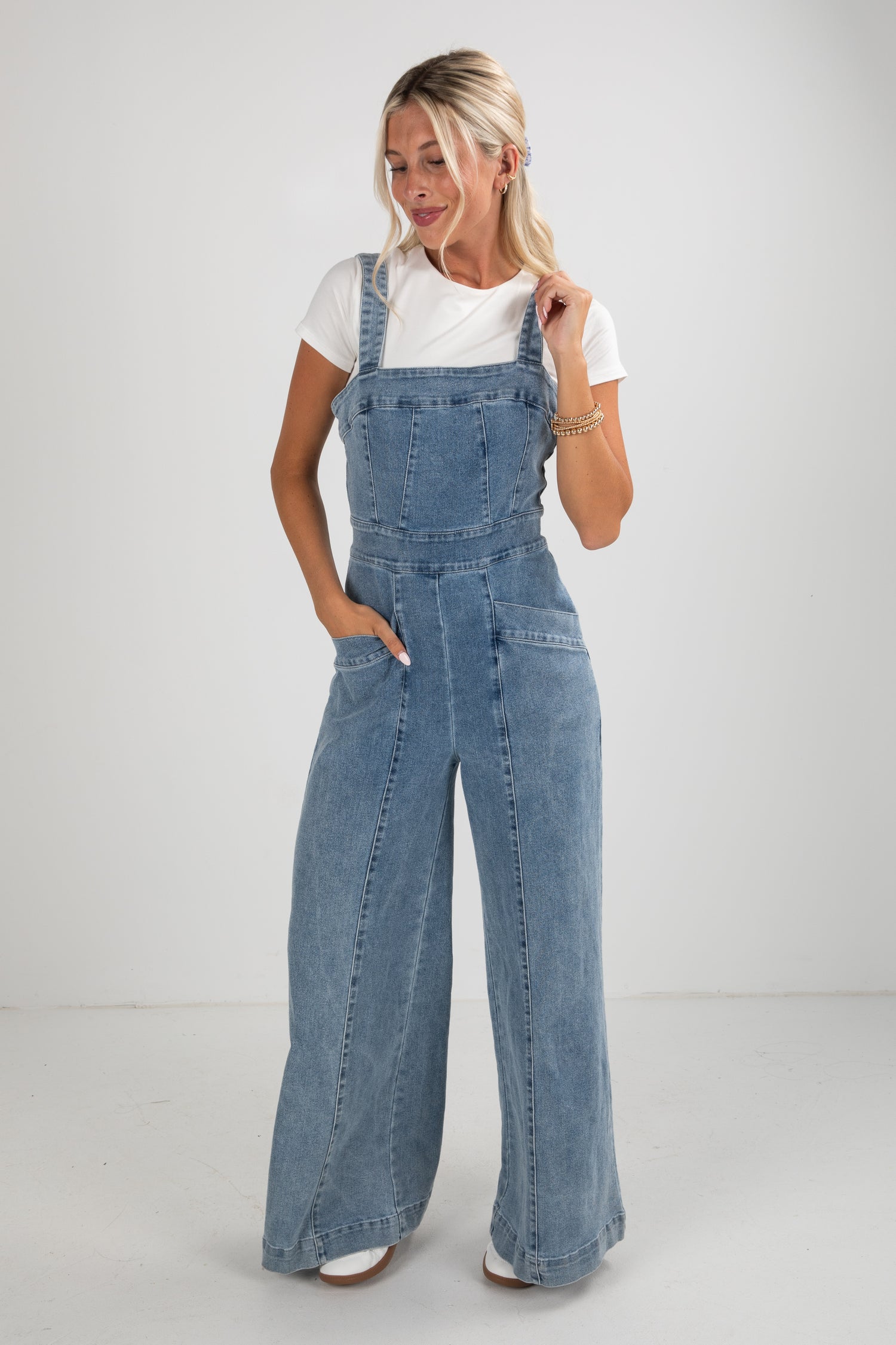 Woman wearing blue denim overalls on a white background
