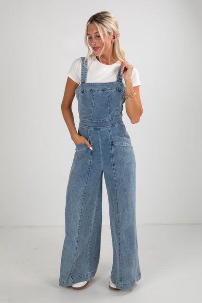 Woman wearing blue denim overalls on a white background