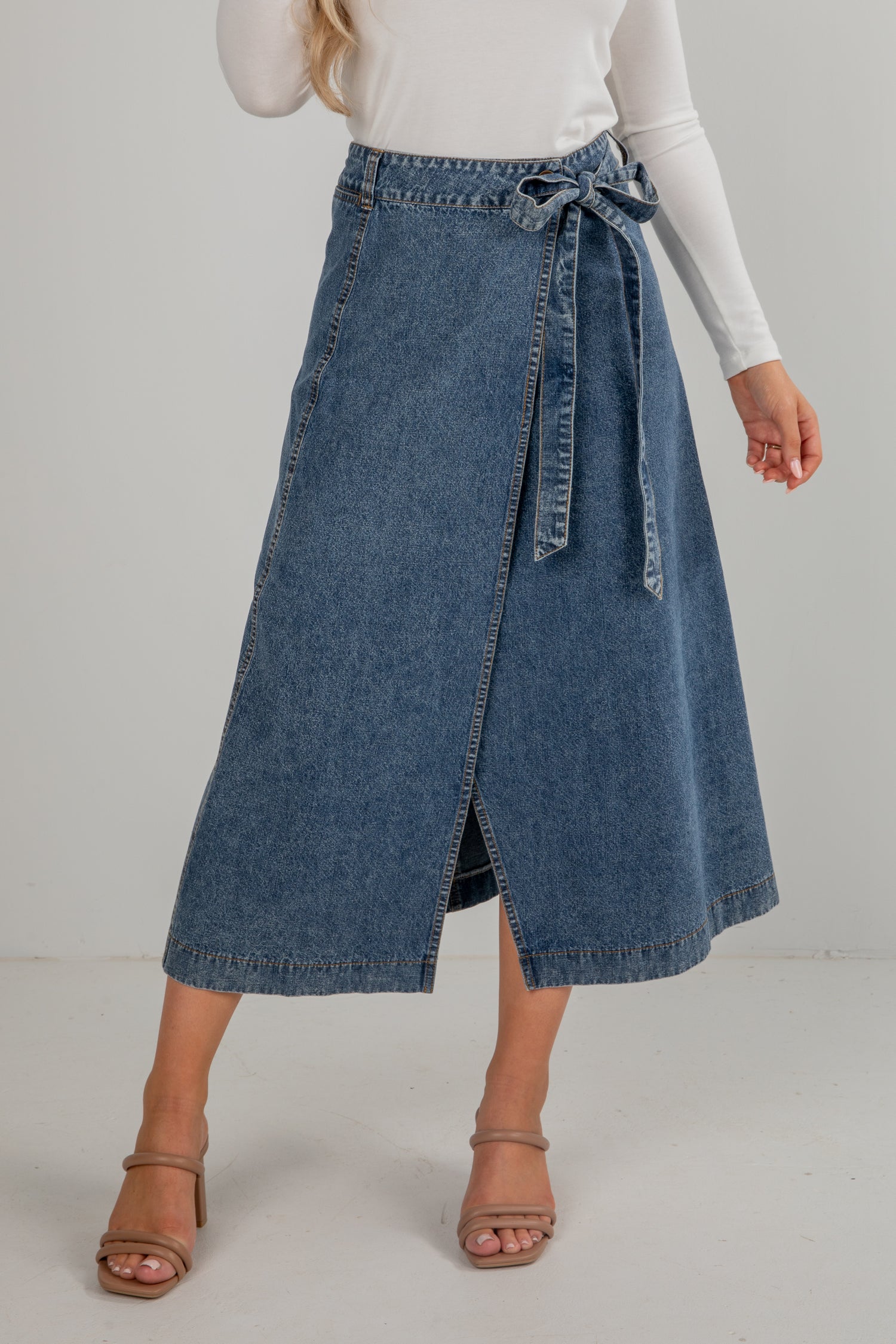 Person wearing a blue denim skirt on a plain background
