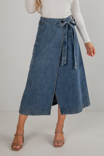 Person wearing a blue denim skirt on a plain background