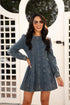 Woman wearing a denim dress with long sleeves in front of a white lattice background