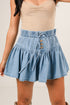 Denim skirt with button details worn by a person on a plain background