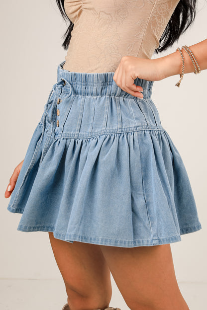 Denim skirt worn by a person on a plain background