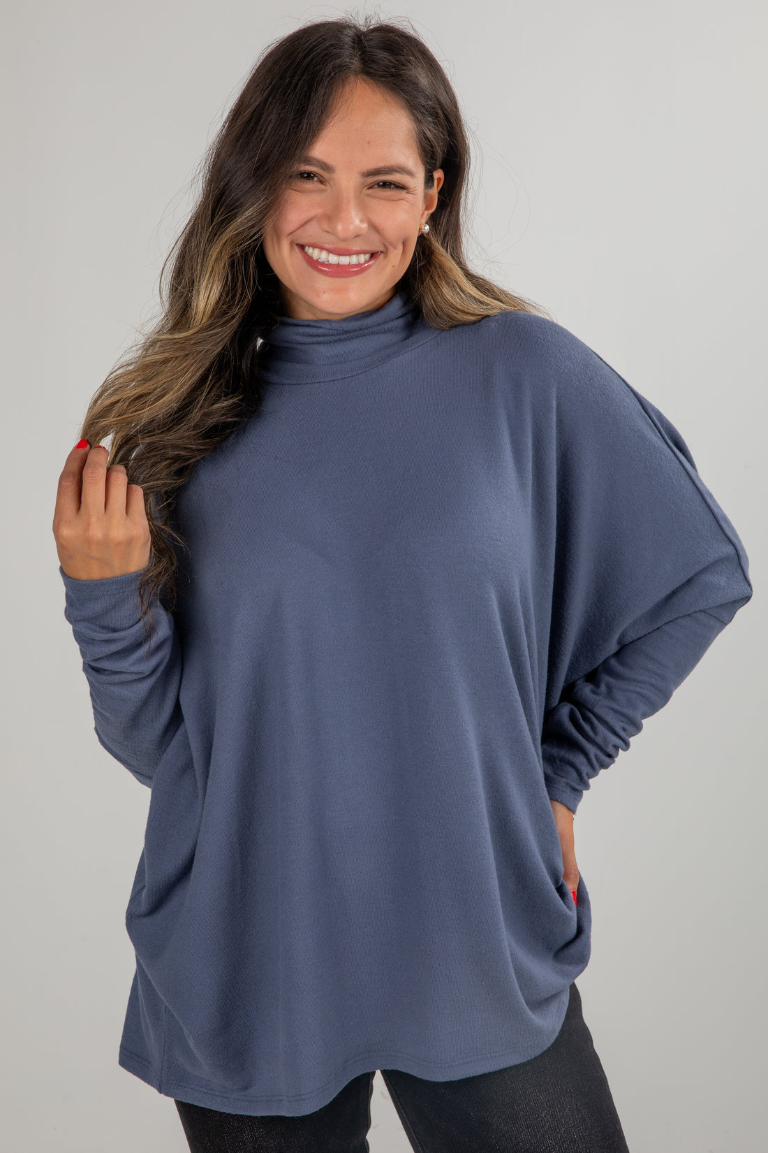 Woman wearing a blue turtleneck sweater against a gray background