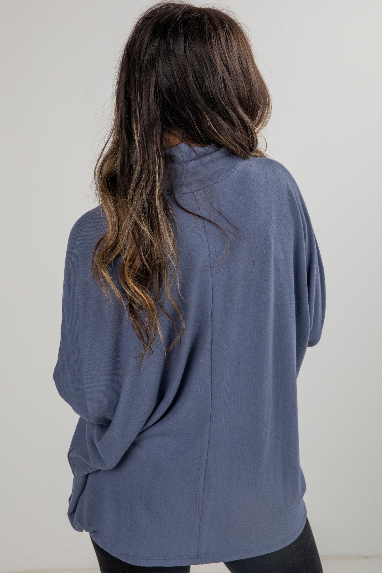 Person wearing a blue sweater against a plain background