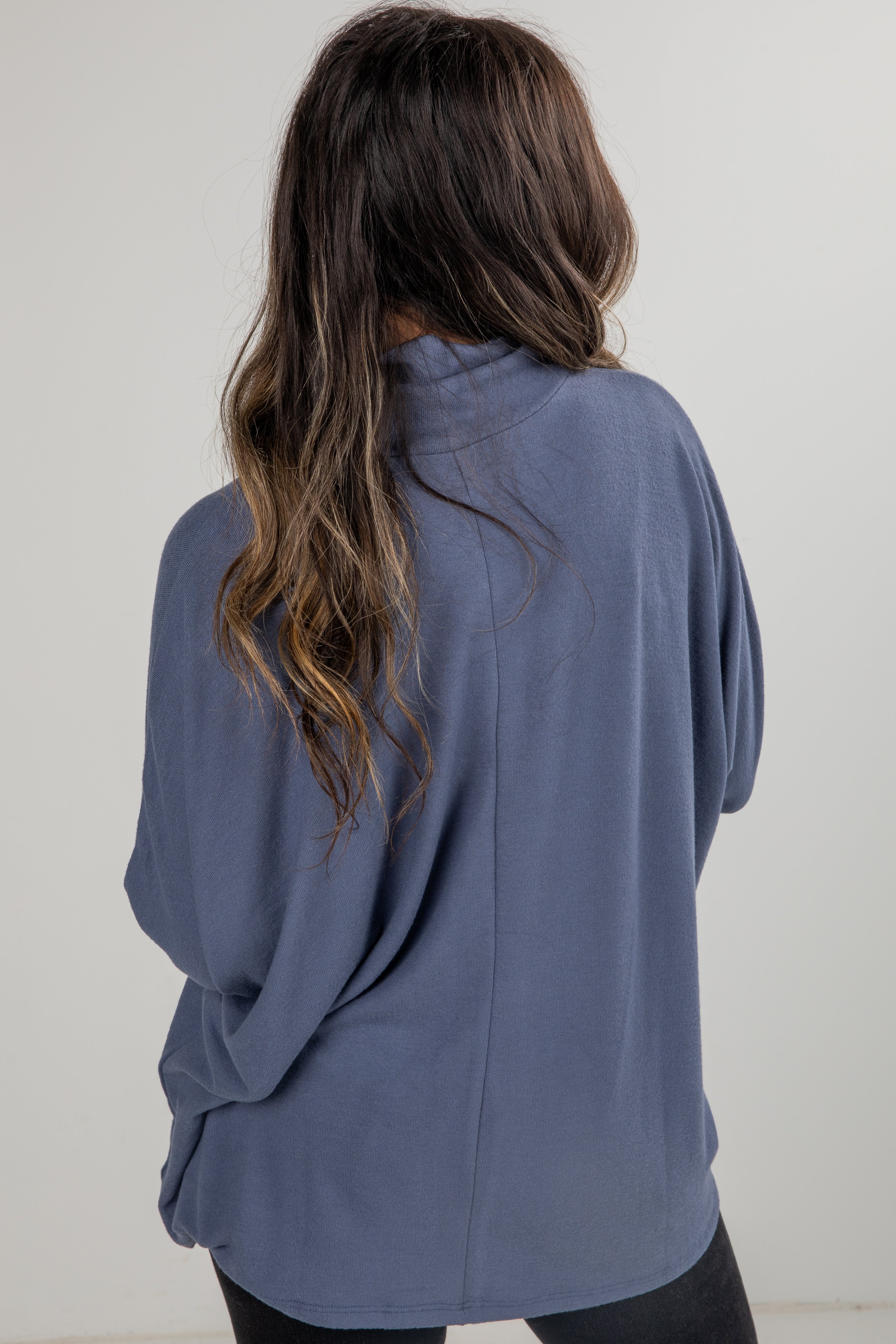 Person wearing a blue sweater against a plain background