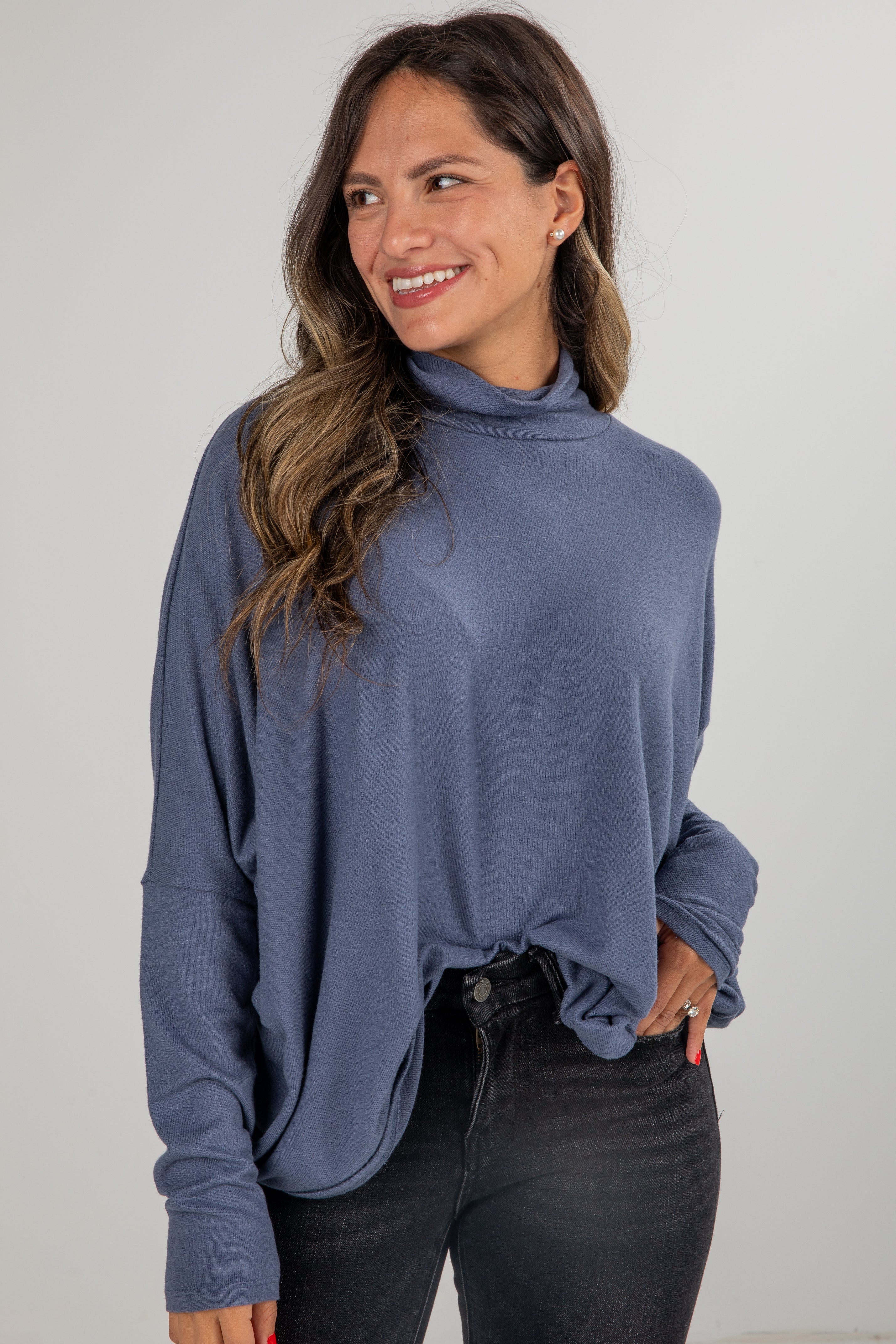 Woman wearing a blue long-sleeve top against a plain background
