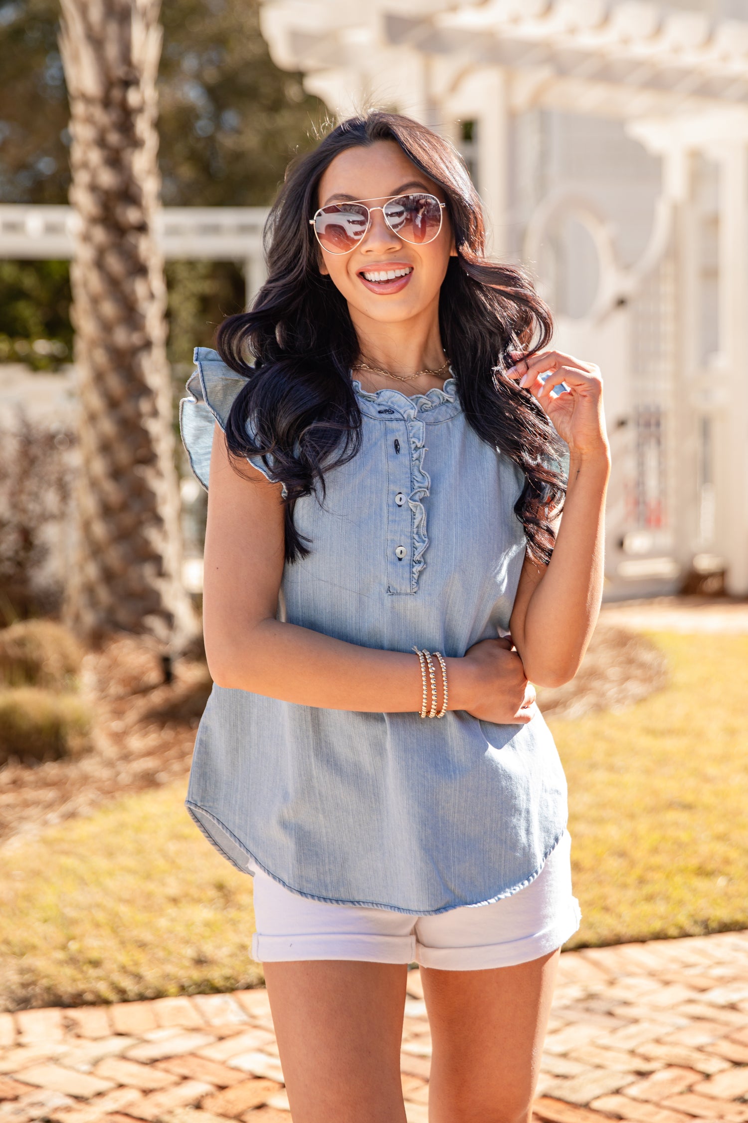 Woman wearing a denim top and white shorts outdoors