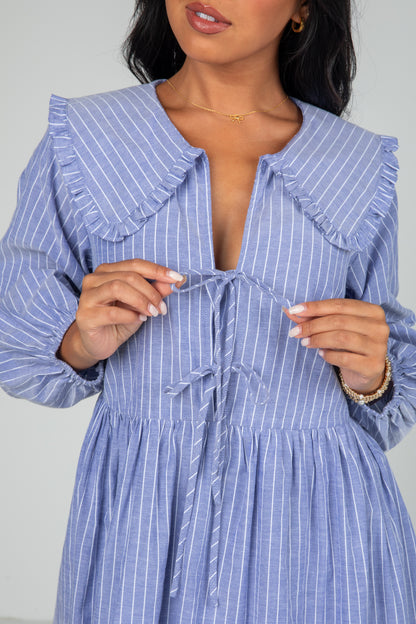 Woman wearing a blue and white striped dress with a plain background
