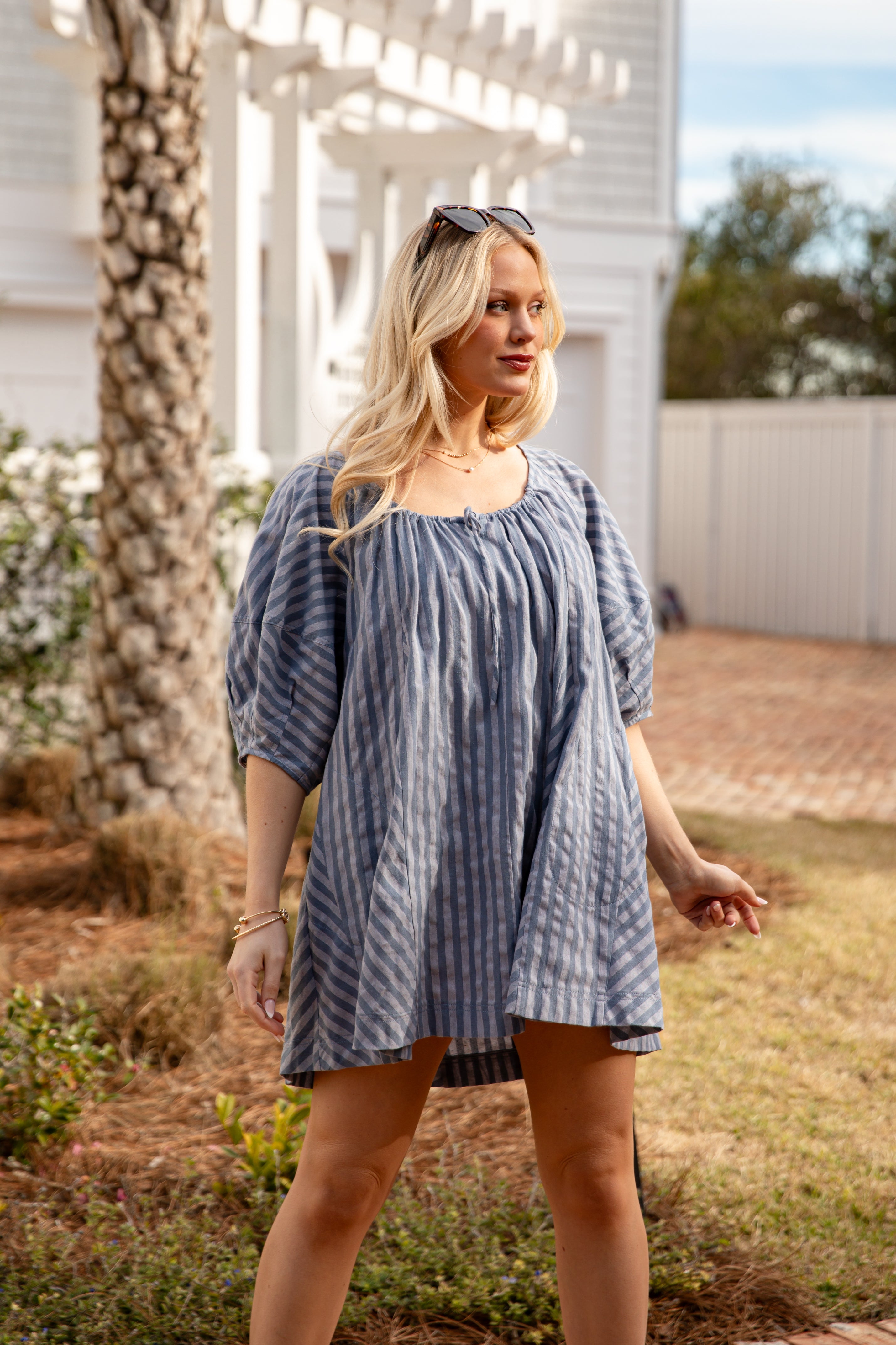 Woman wearing a blue striped dress standing outdoors.