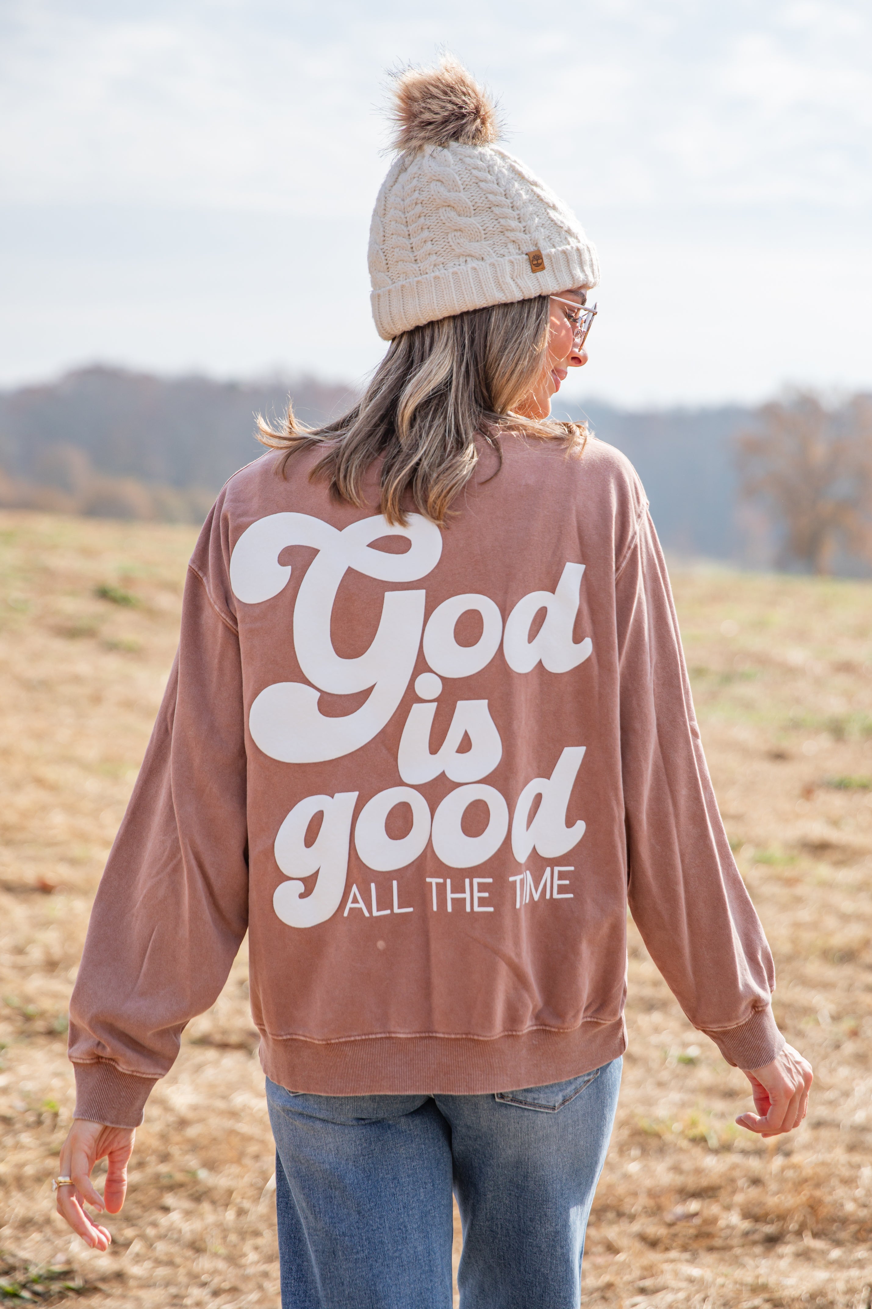 Person wearing a brown sweatshirt with &