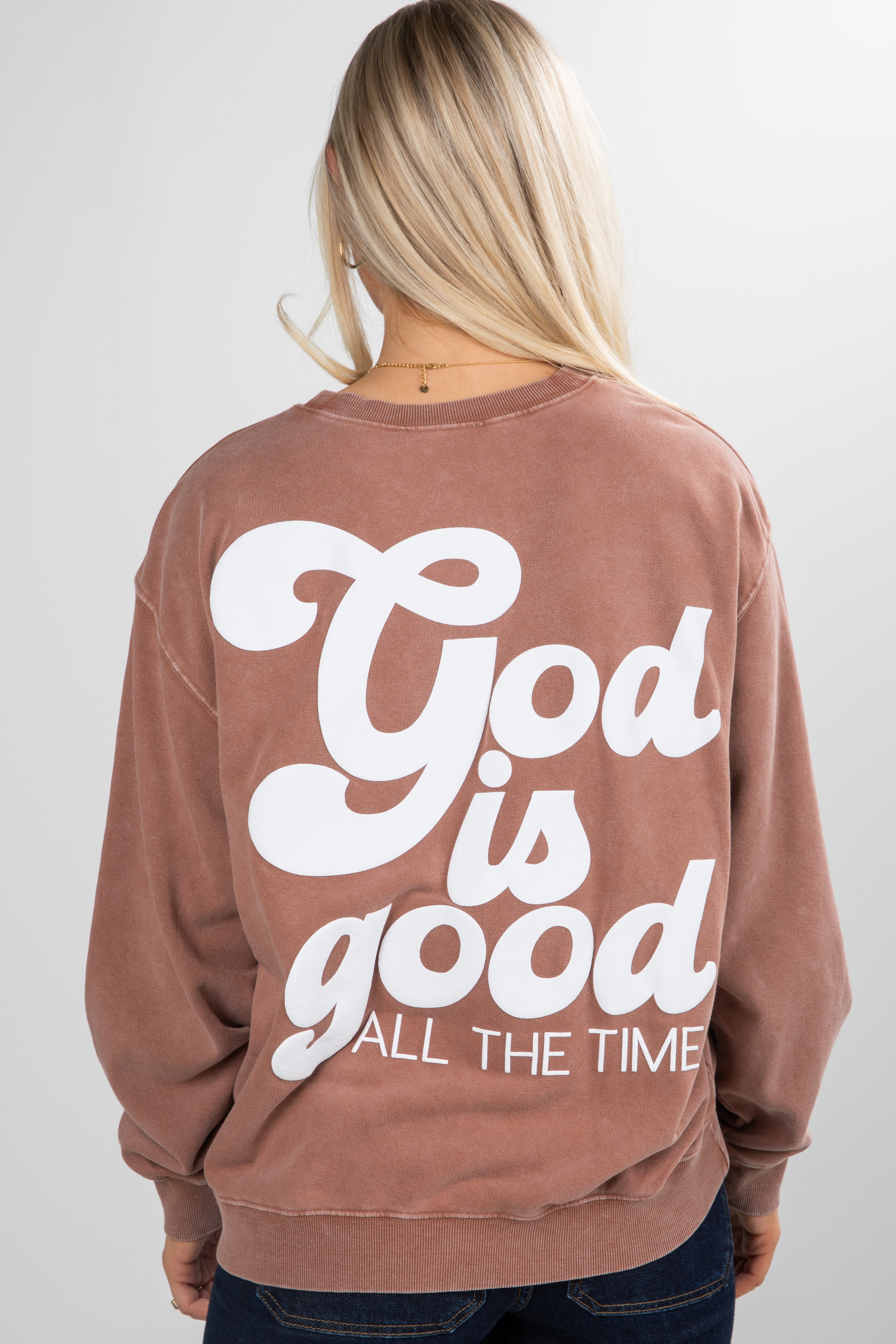 Person wearing a brown sweatshirt with &