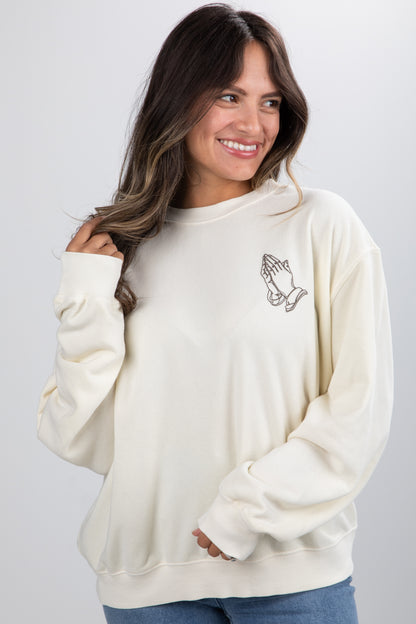 Woman wearing a cream-colored sweatshirt with a design on a plain background