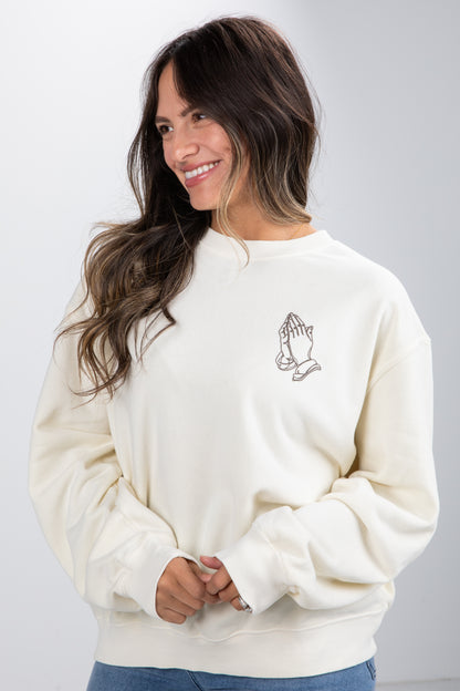 Woman wearing a cream sweatshirt with a small design on a plain background