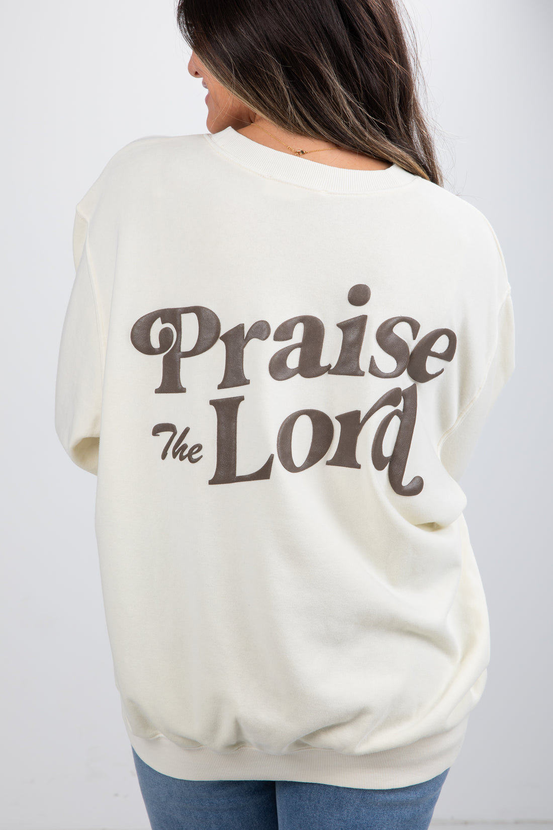 Person wearing a cream-colored sweatshirt with &