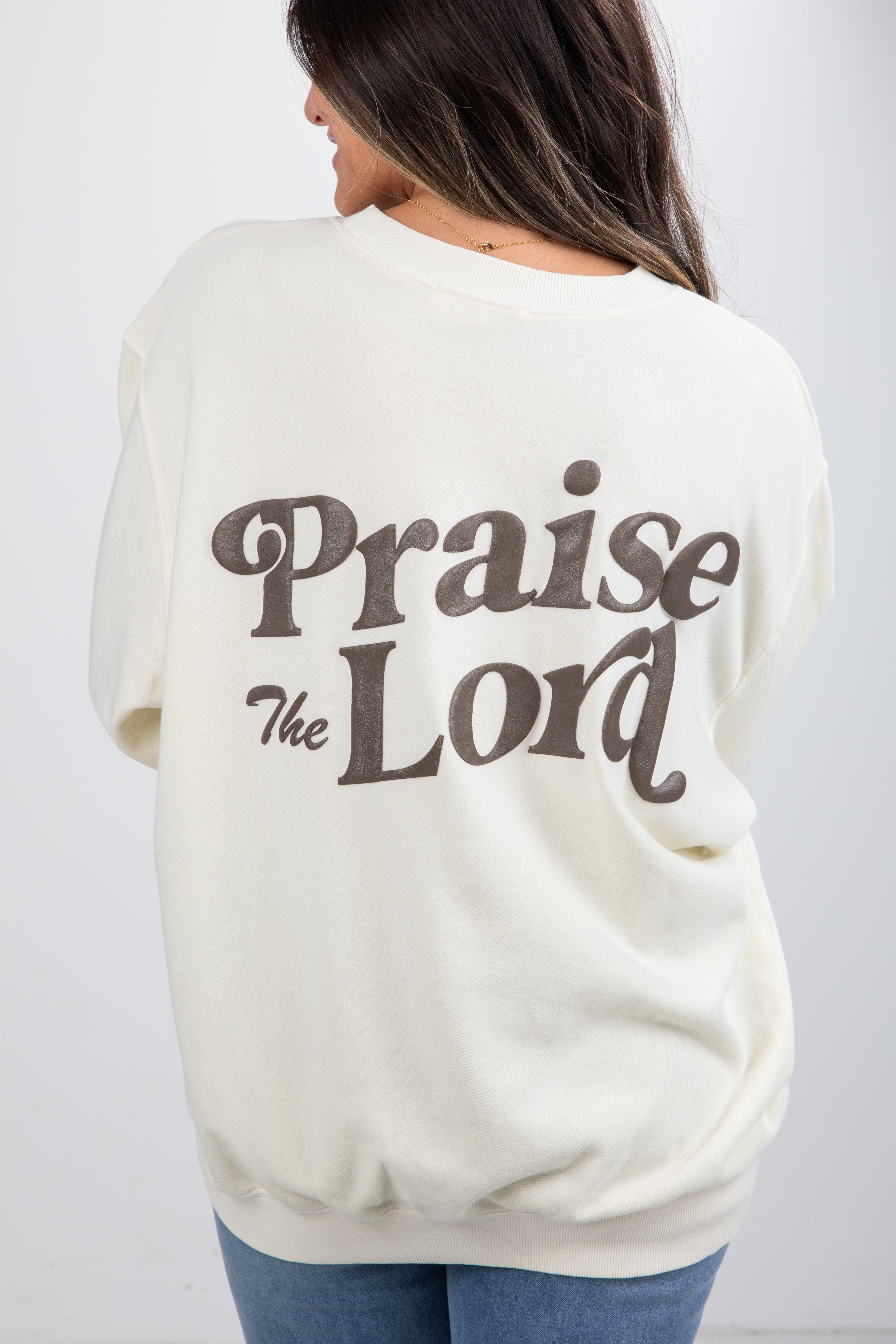 Person wearing a cream-colored sweatshirt with &