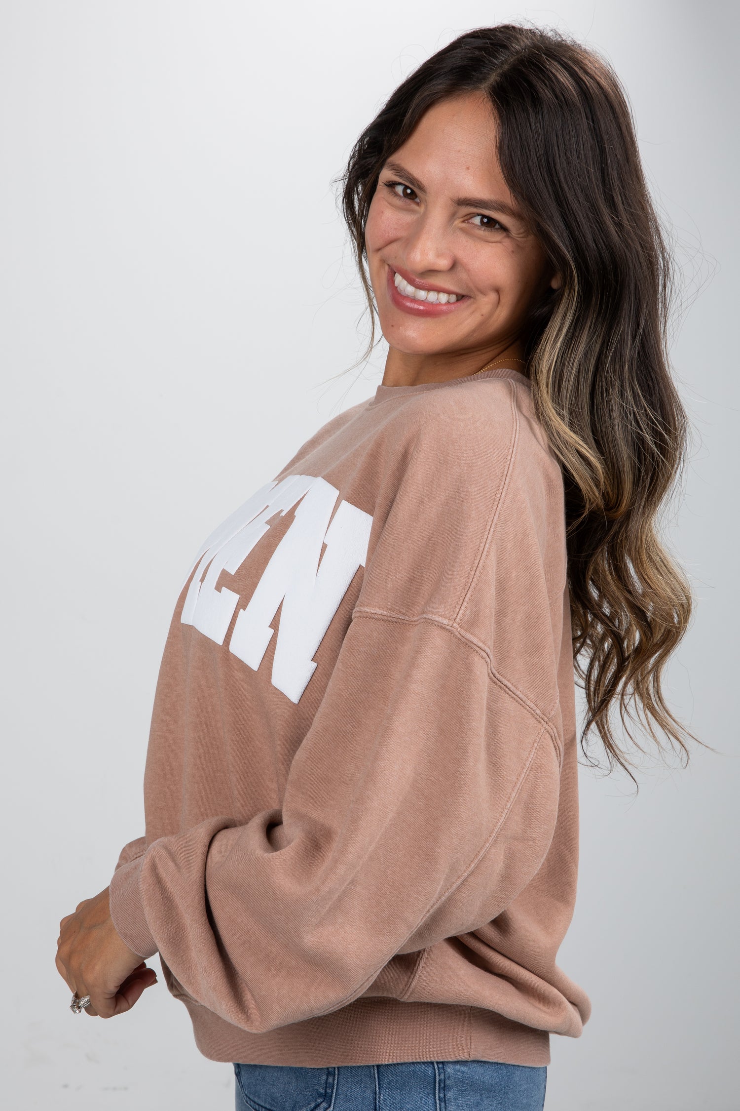 Woman wearing a beige oversized sweatshirt with text on a plain background