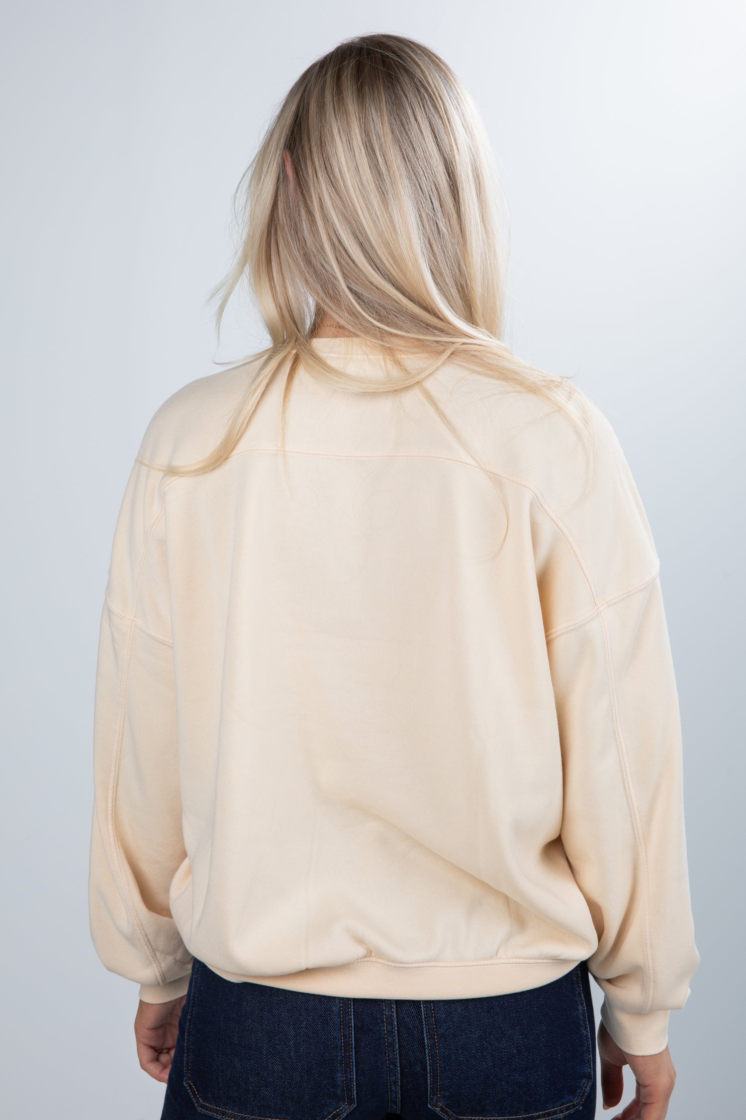 Person wearing a beige blouse with long sleeves on a plain background