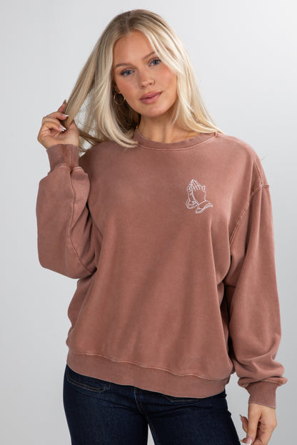 Woman wearing a brown sweatshirt with a small graphic on a plain background