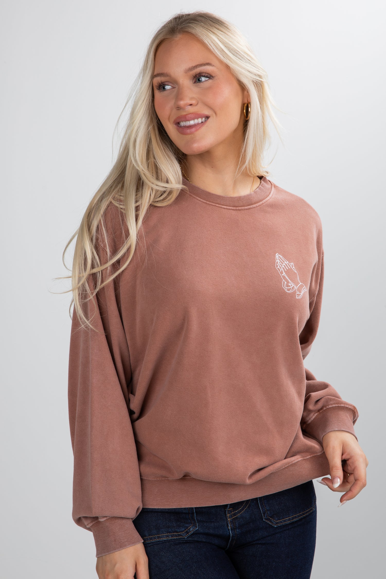 Woman wearing a brown sweatshirt with a small graphic on a white background