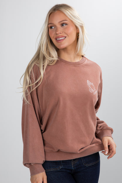 Woman wearing a brown sweatshirt with a small graphic on a white background
