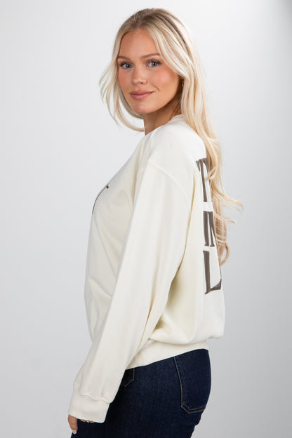 Woman wearing a cream-colored sweater with a graphic design on a white background