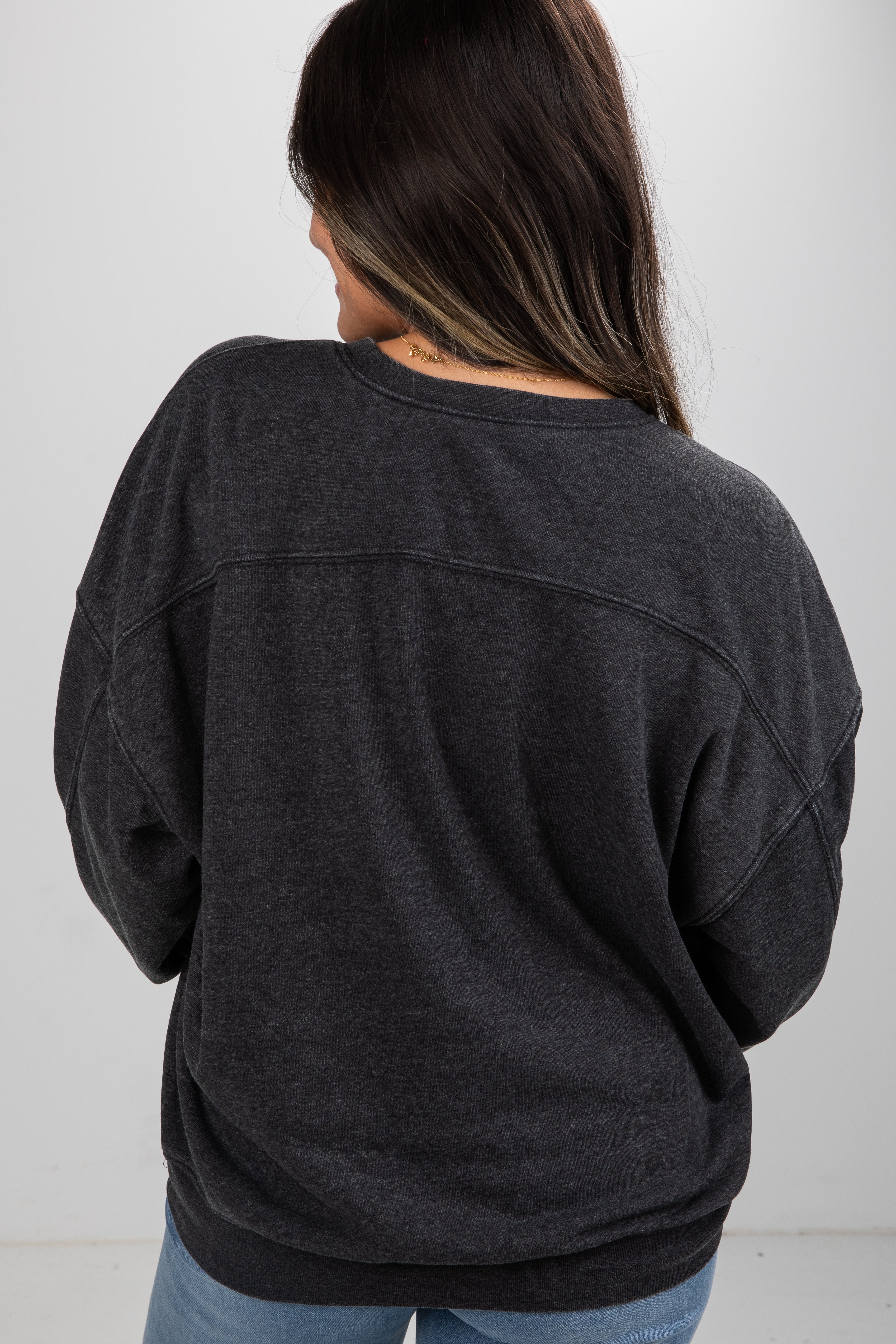 Person wearing a dark gray oversized sweater against a white background