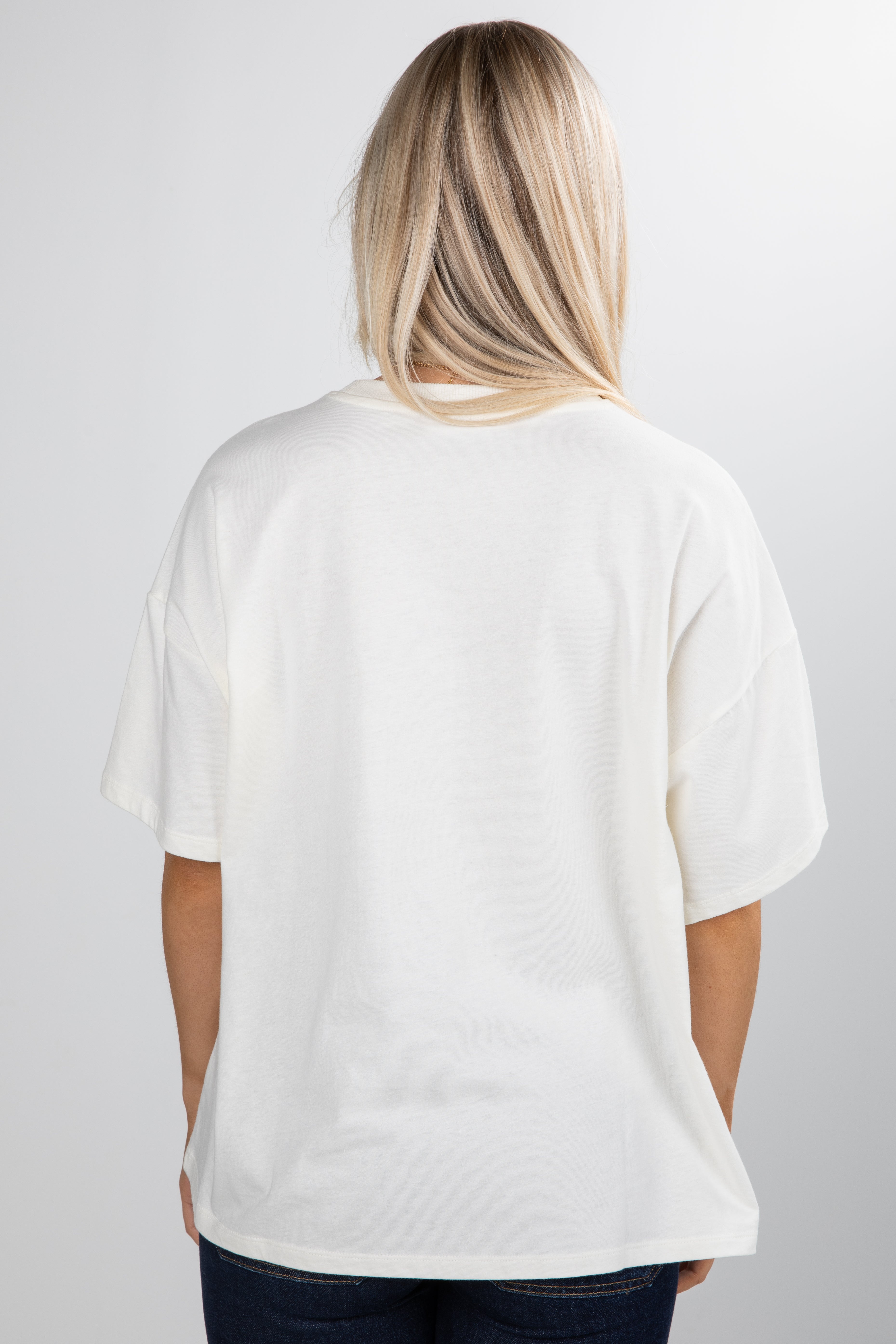 Person wearing a plain white t-shirt on a light gray background