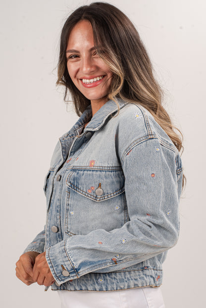 Woman wearing a light blue denim jacket with subtle distressing on a plain background