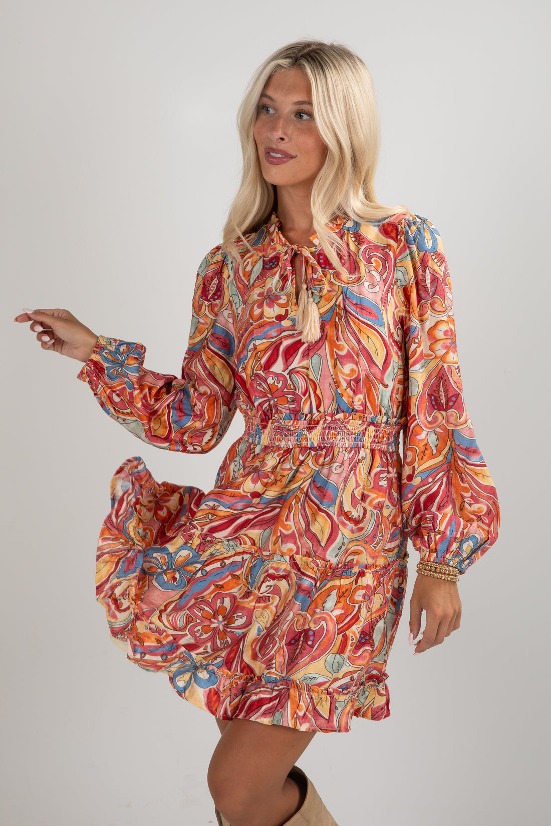 Woman wearing a colorful patterned dress on a plain background