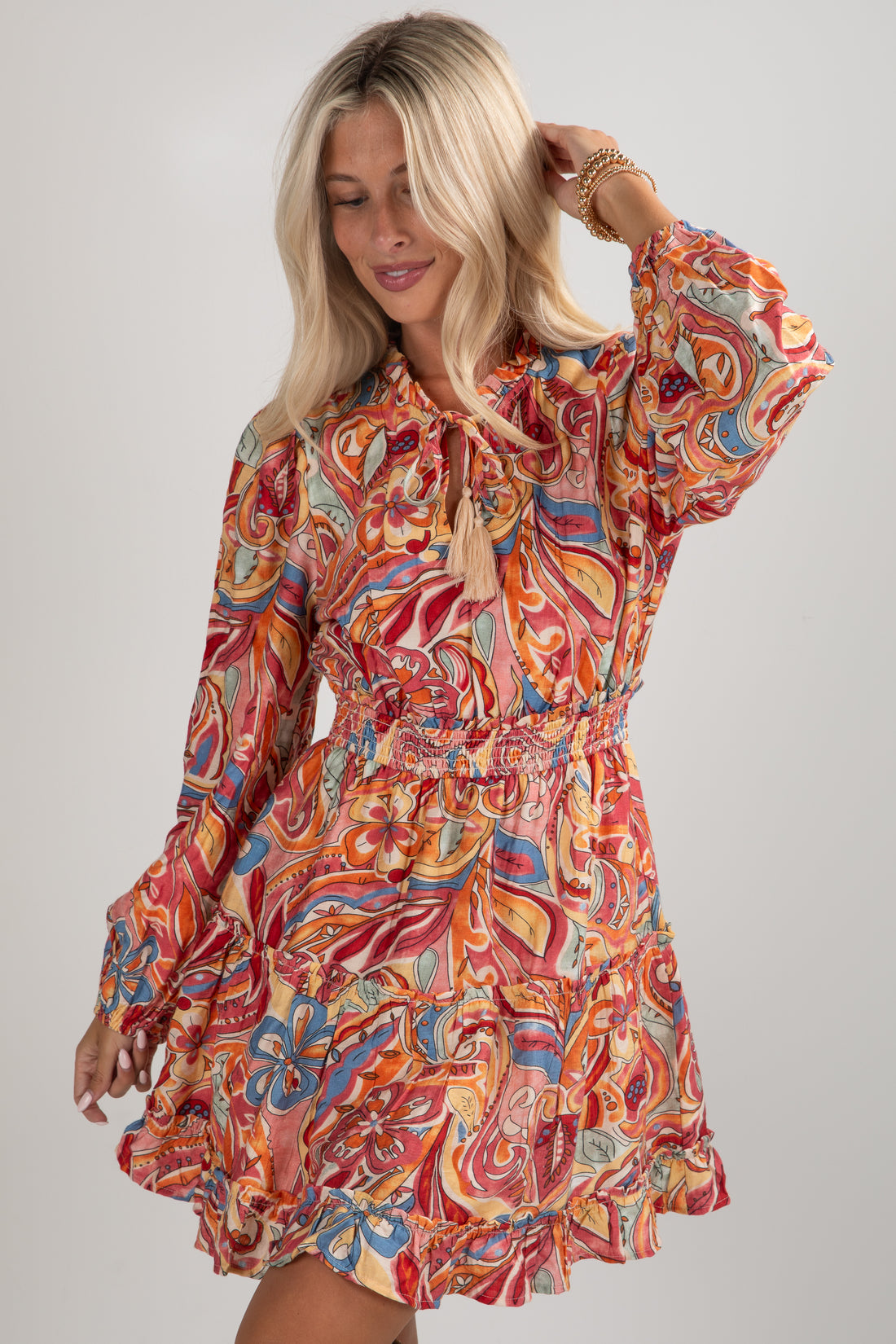 Woman wearing a colorful patterned dress on a plain background