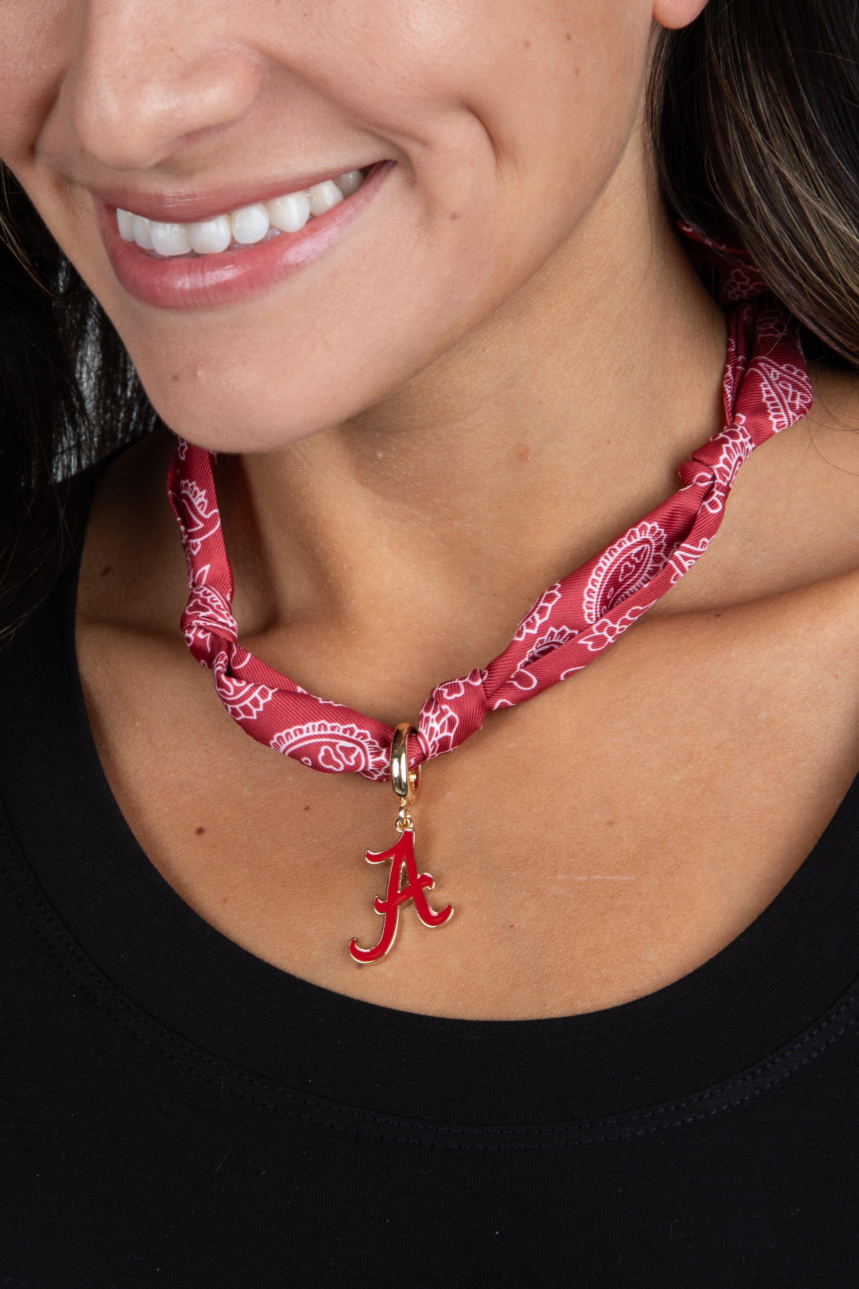 Person wearing a red bandana necklace with a letter &
