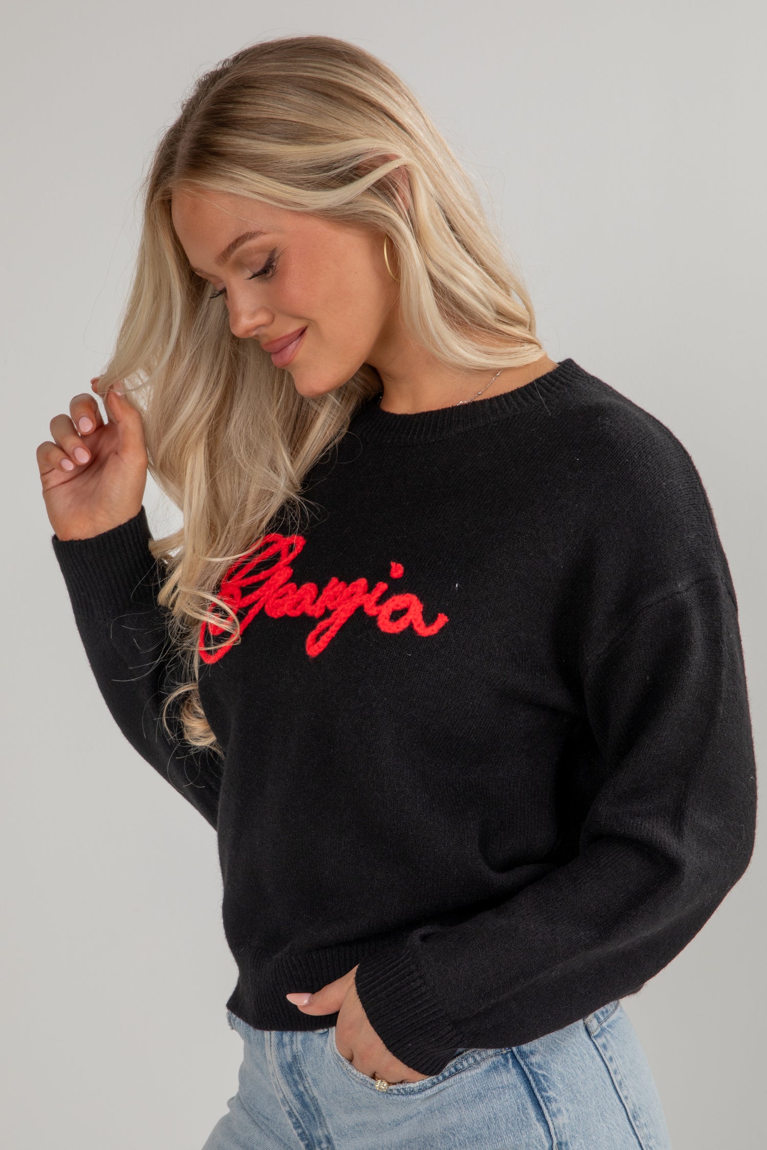 Woman wearing a black sweater with red text on a plain background