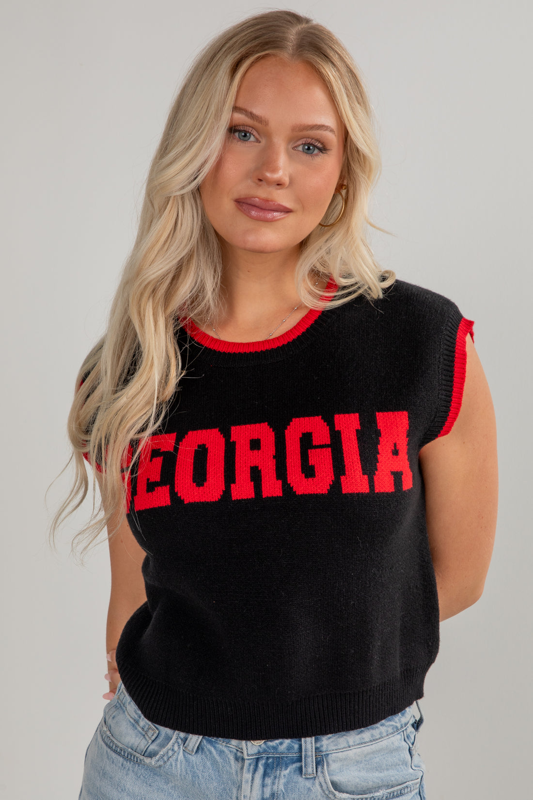 Woman wearing a black sleeveless sweater with &